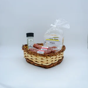 Geschenkkorb Piz Corvatsch mit Bündner Kräutersalz, Chiliwurst, Knoblauchwurst und Vatgas Teigwaren in Kuhform, präsentiert in einem geflochtenen Korb vor hellem Hintergrund.